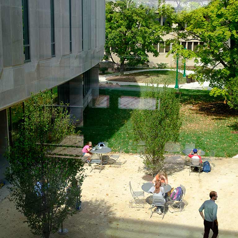 Students are sitting around tables in the courtyard.